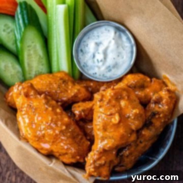 Chicken wings in a basket with veggies and dip.