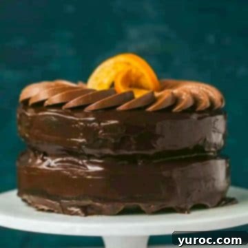 Chocolate orange cake on a white stand with a dark blue background.