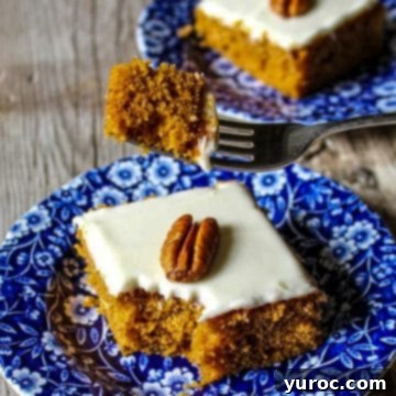 Pumpkin bar on a blue flowered plate with a piece being held on a fork, with another piece in the background.