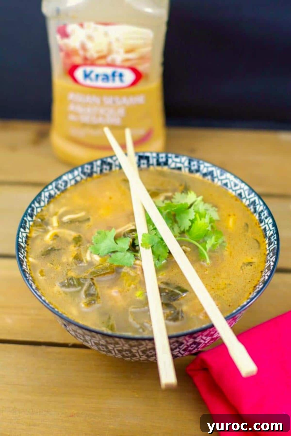 Quick Asian beef soup in a checkered bowl with chopsticks on top of the bowl and a bottle of Asian Sesame salad dressing in the background